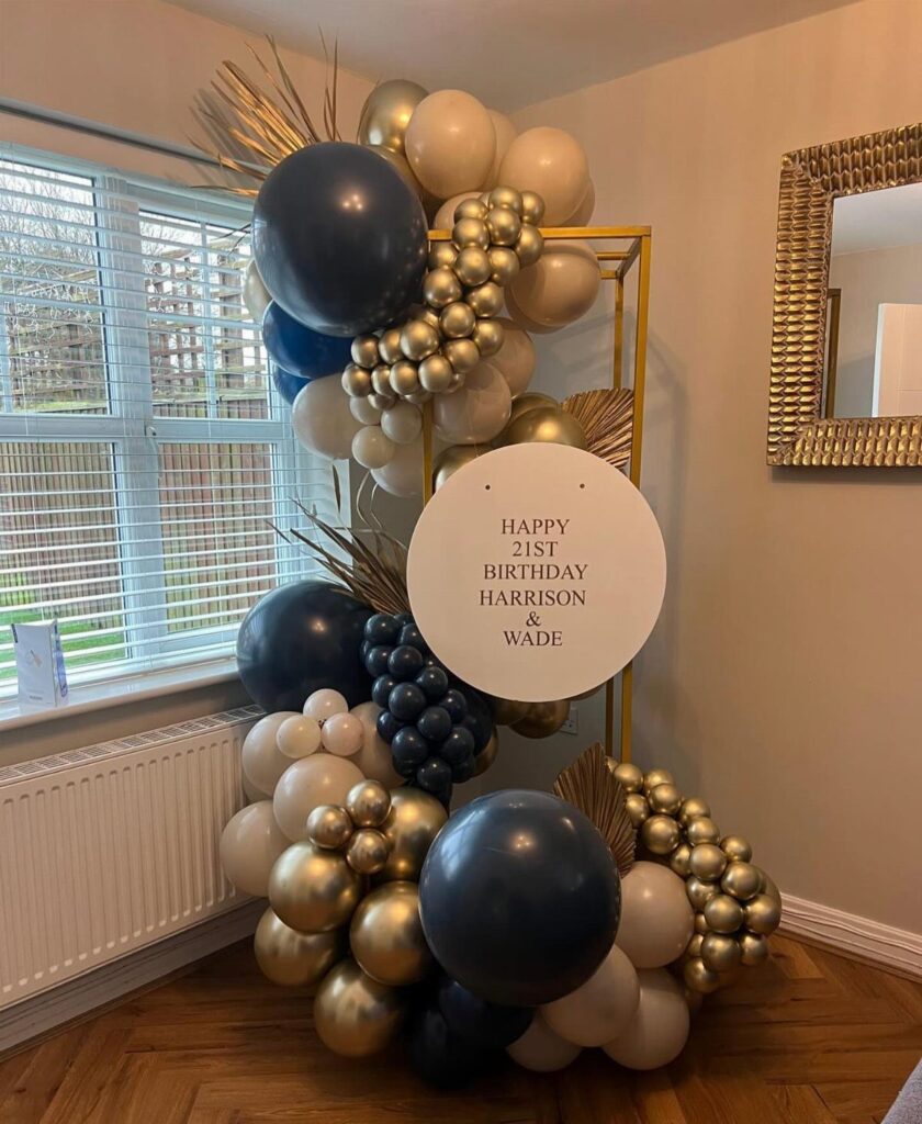 Balloon arch with navy, gold, and cream balloons and a 21st birthday sign.