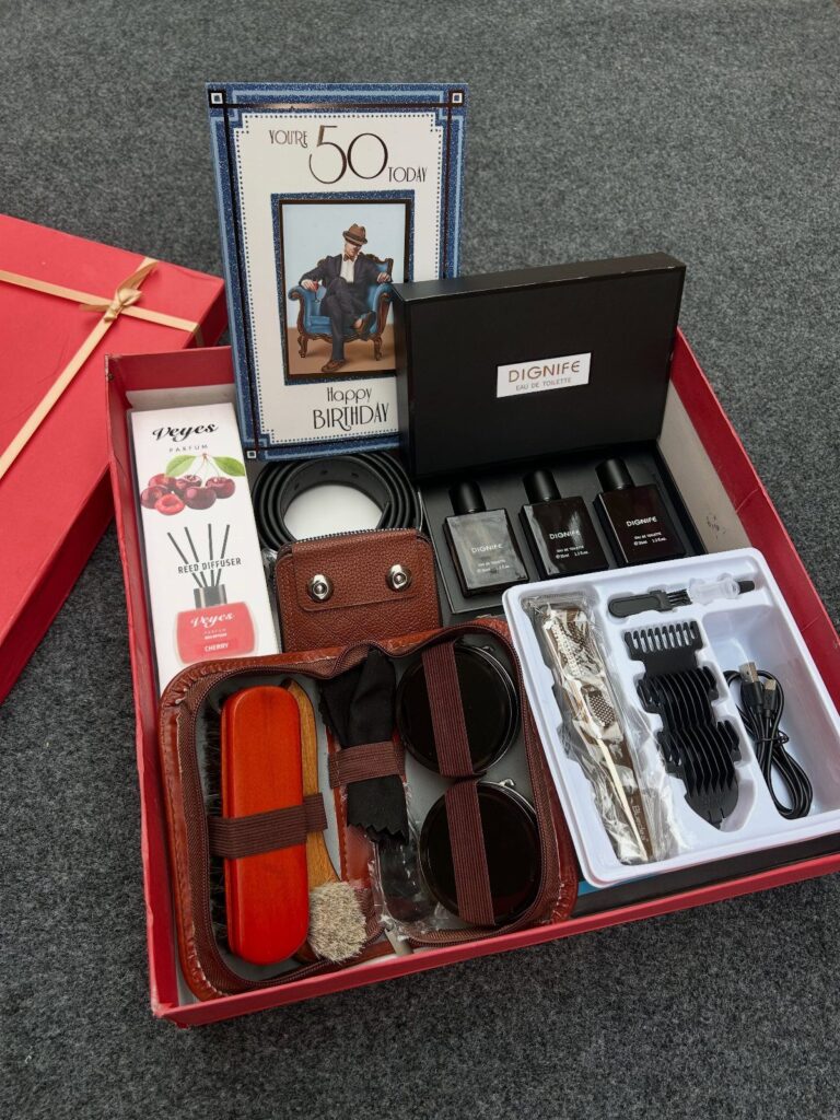 Red gift box filled with grooming tools, fragrances, and a 50th birthday card.