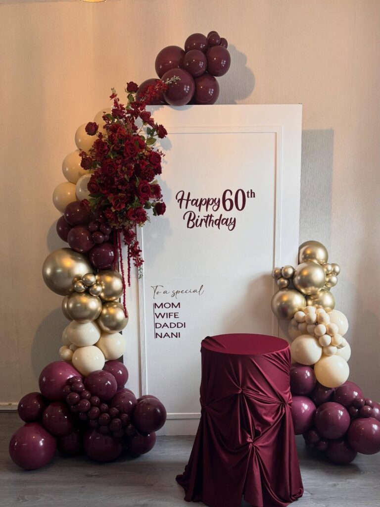 Birthday party backdrop with burgundy and gold balloons and Happy 60th Birthday text