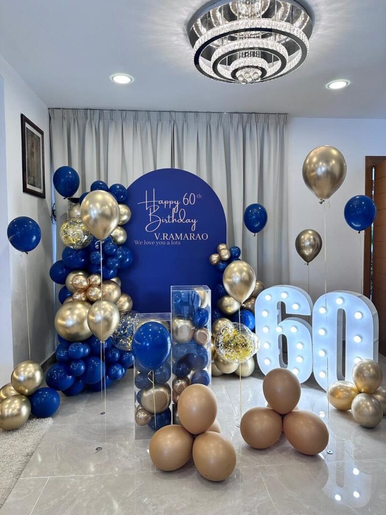 Blue and gold balloon decorations with large glowing 60 numbers for a birthday.
