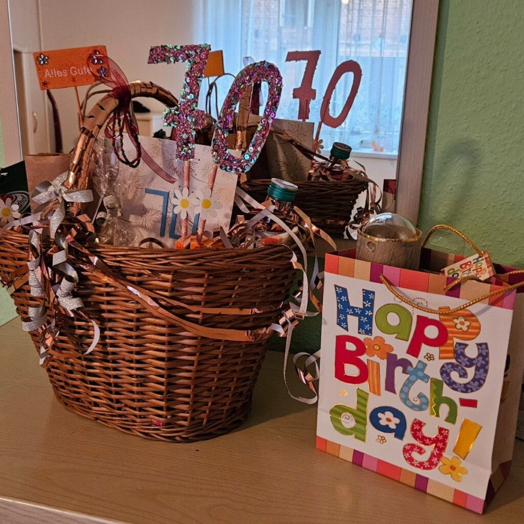 Wicker gift basket with a glittery 70 topper and a colorful birthday bag.