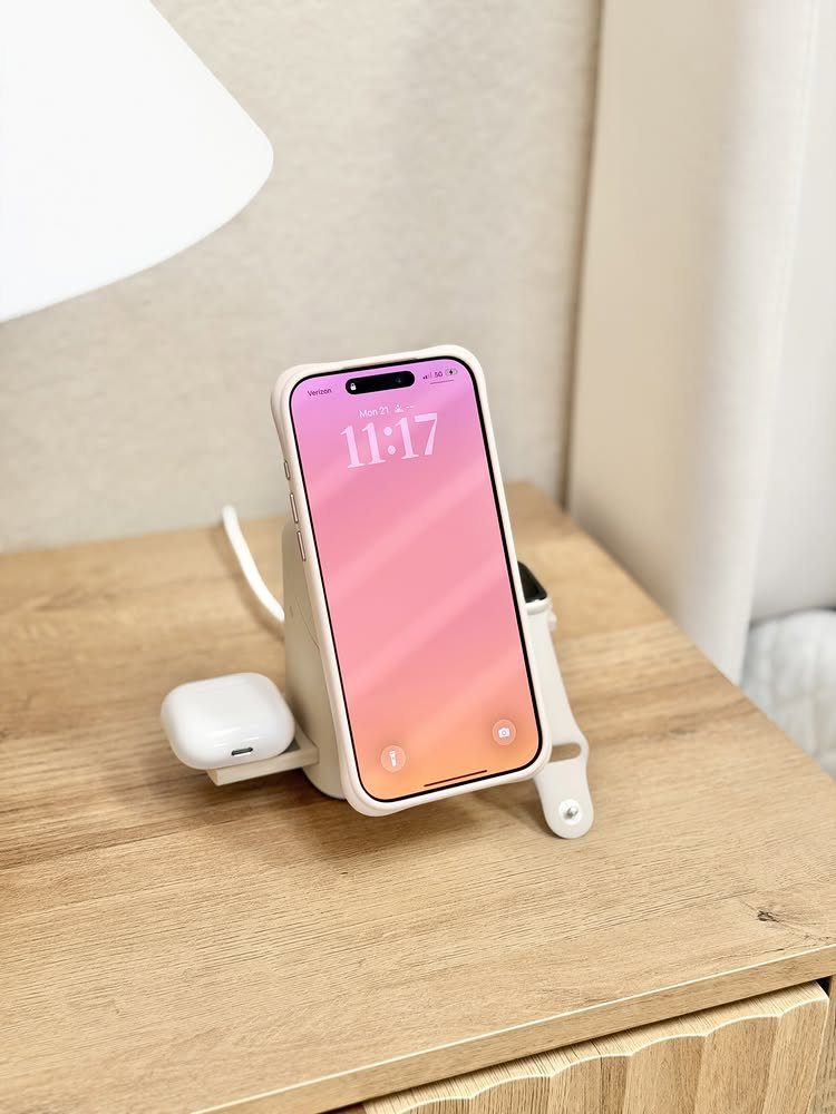 White wireless charging station holding a smartphone and wireless earbuds on wooden table