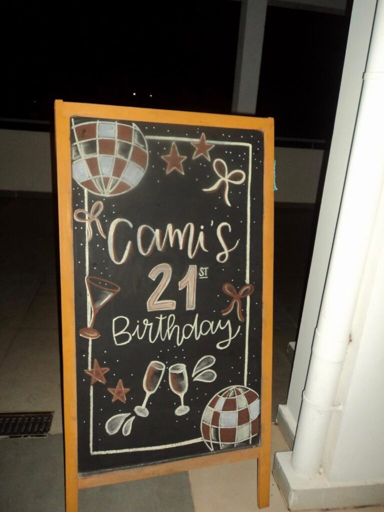 Chalkboard with wooden frame featuring 21st birthday decorations and personalized text.