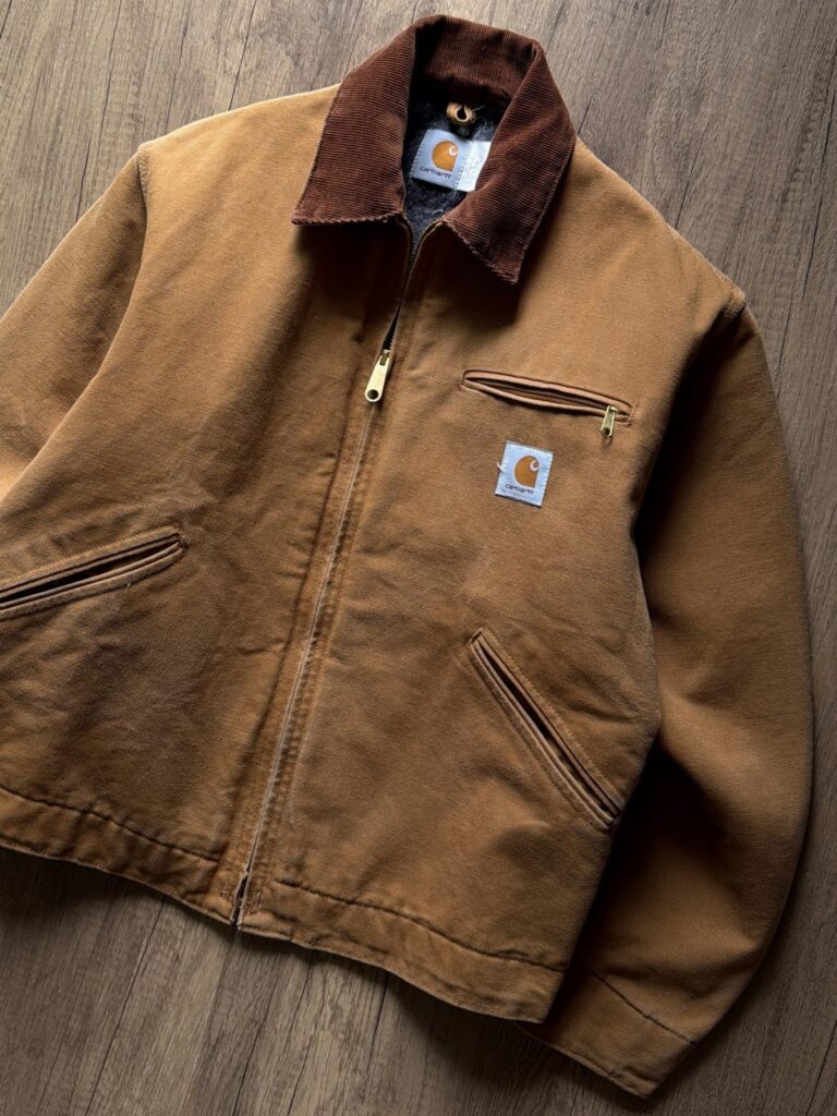 Brown corduroy Carhartt jacket with a dark collar laid on a wooden floor
