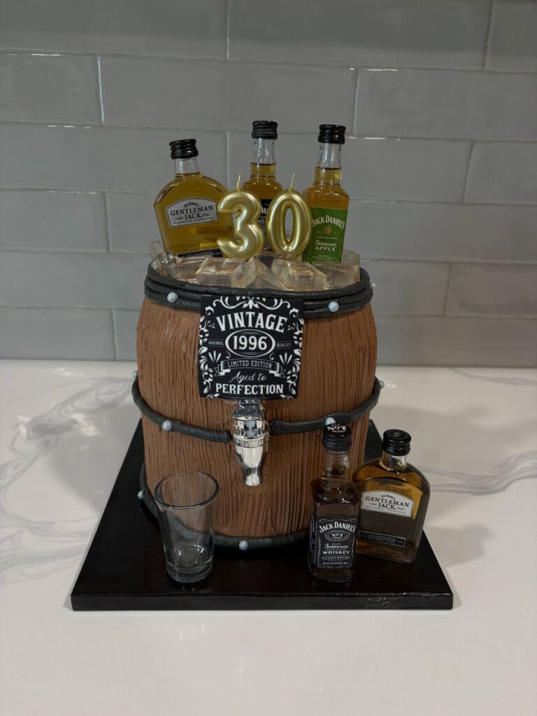 Wooden whiskey barrel cooler with ice, miniature liquor bottles, and a 30th birthday candle.