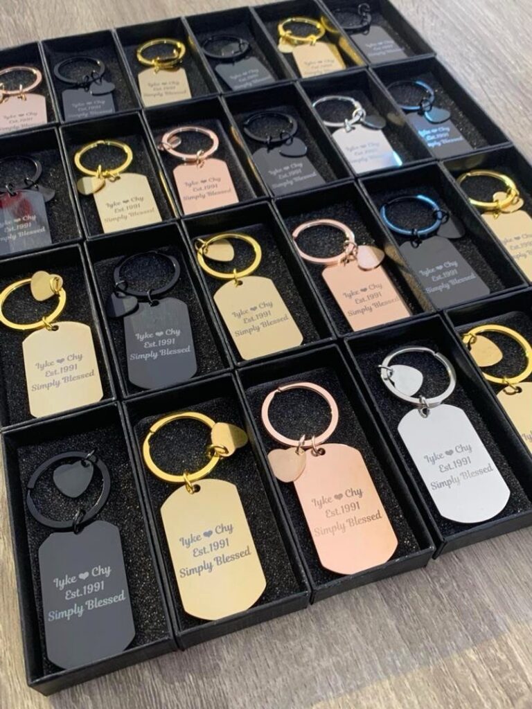 Engraved metal keychains in various colors presented in individual black gift boxes.